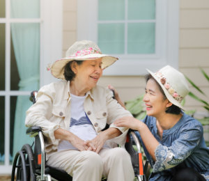 senior women relax on wheelchair in backyard with her caregiver